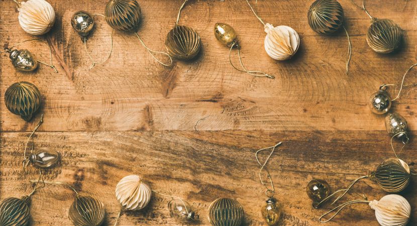 Gold and cream folded tree ornaments, and baubles arranged on wooden board, copy space