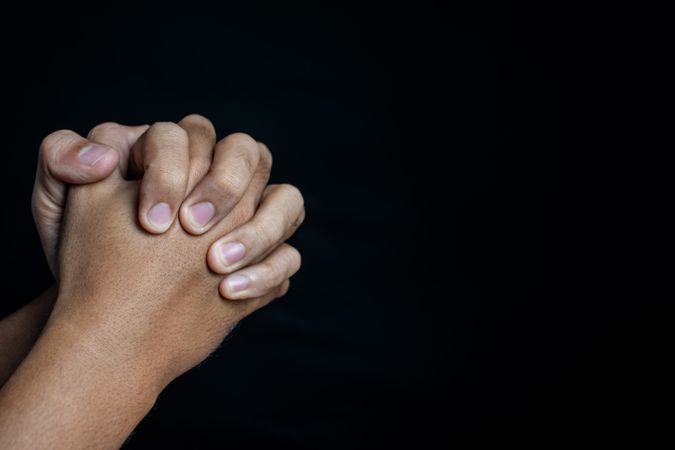male hands praising or worship gesture isolated on dark background. religion and spirituality concept