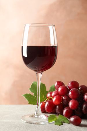 Grape and glass with wine on grey background, space for text
