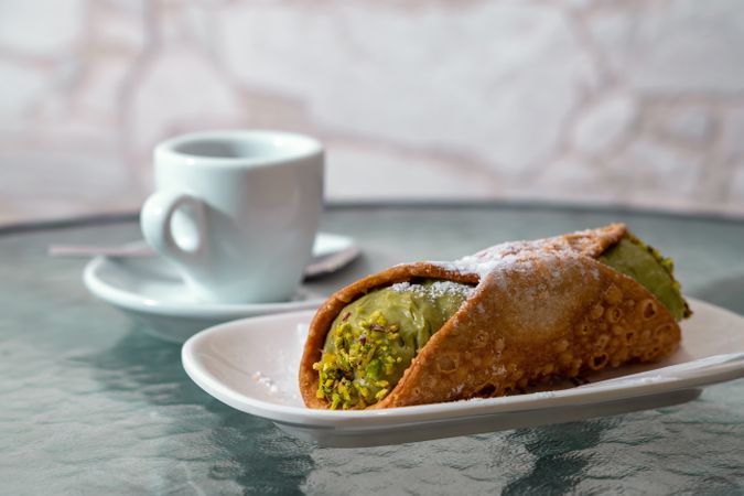Traditional Italian pistachio cannoli dessert served with espresso coffee ceramic plate authentic sicilian pastry sweet food closeup