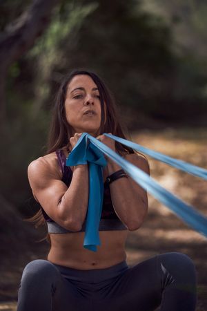 Fit woman doing exercise with resistance band in nature