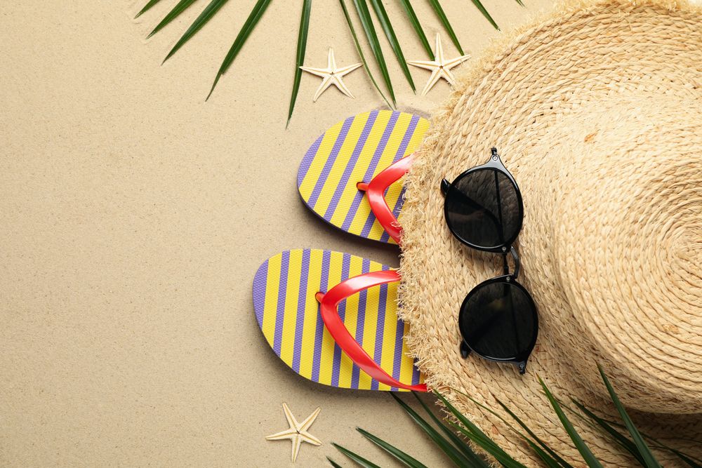 Summer vacation accessories on sea sand background, space for text