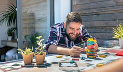Bearded man catching jenga game piece in rooftop party