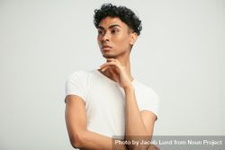 Portrait of a young man standing with his hand on chin and looking away 5rLYpb