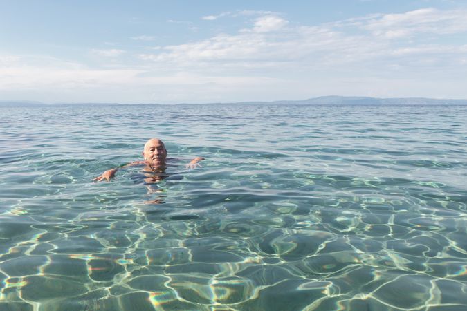 Mustached mature man swimming in clear water