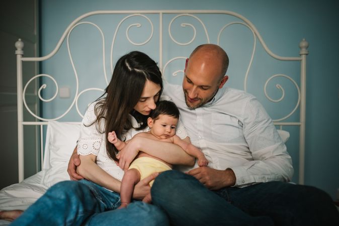 Parents hugging baby on bed