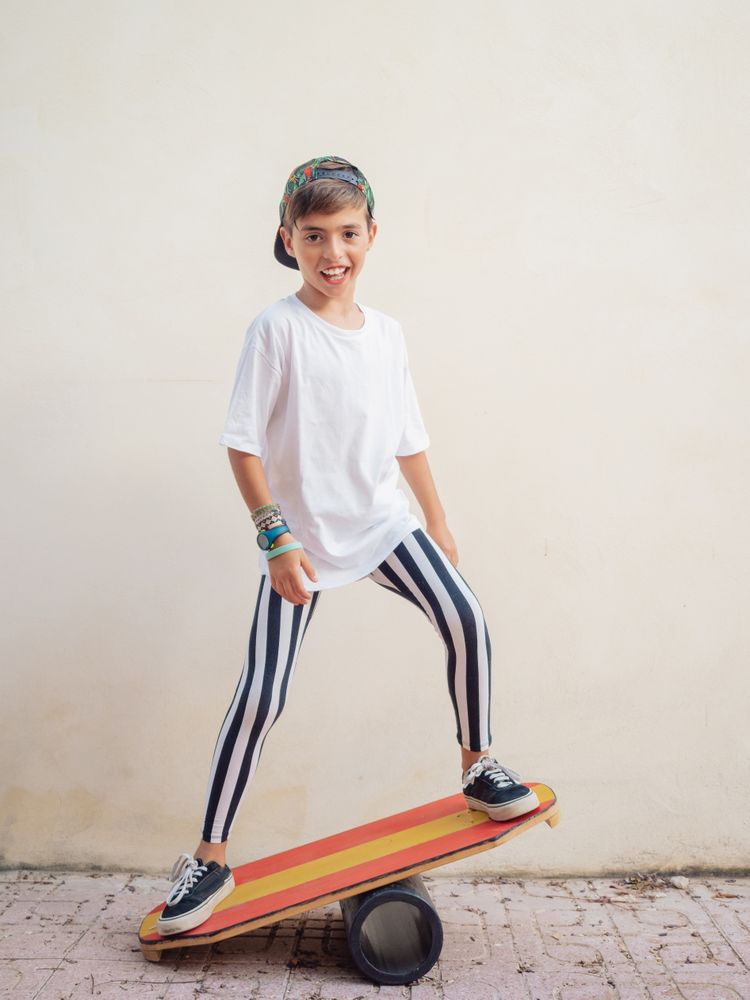 Cheeky boy standing on colorful board and swinging