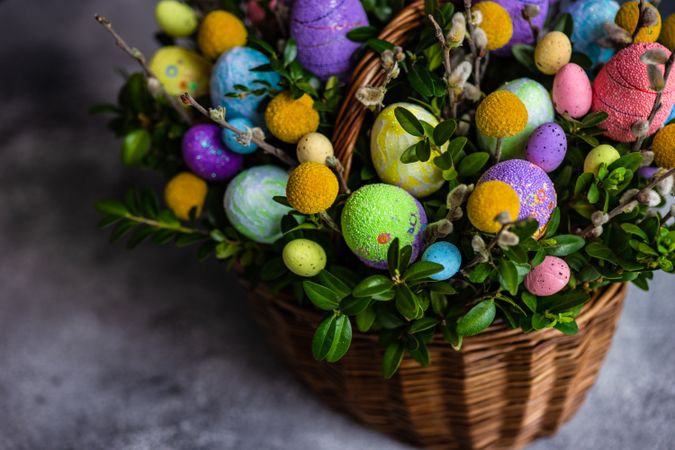 Colorful Easter eggs & leaves in decorative basket