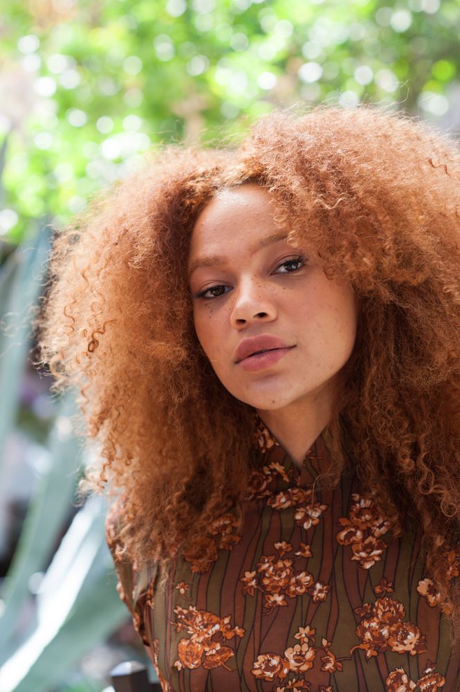 Young woman with afro looking at camera with head tilted