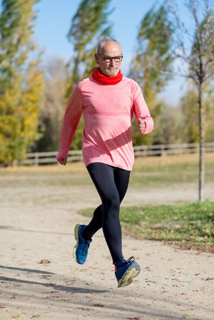 Older male with grey hair sprinting in park