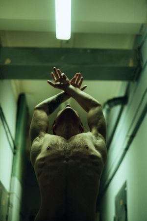 A shirtless man stretching his arms