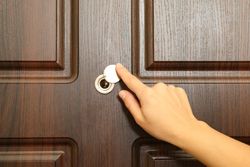 Woman hand hold peephole of wooden door