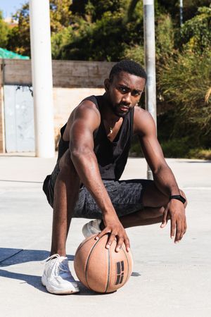 Confident Black sportsman on basketball court in summer