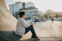 A woman sitting on a ramp in a skatepark 4O38v4