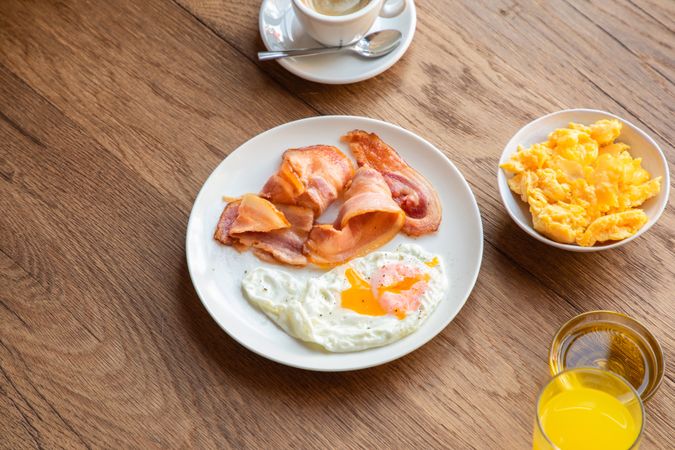 Tasty bacon and eggs with juice at table
