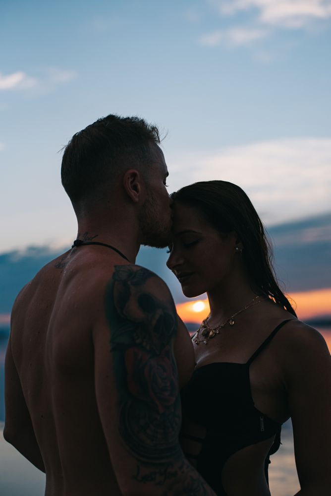Couple hugging on beach of lake at sunset