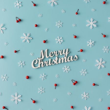 Christmas pattern made of snowflakes and red berries with “Merry Christmas” on blue background