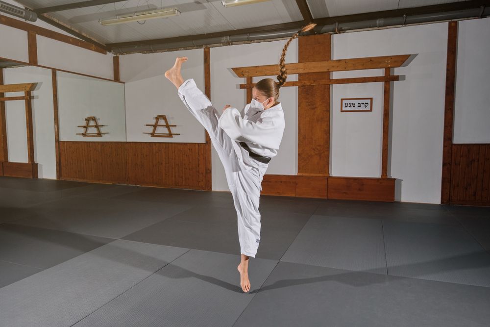 Woman wearing a mask with a white kimono kicking in the air