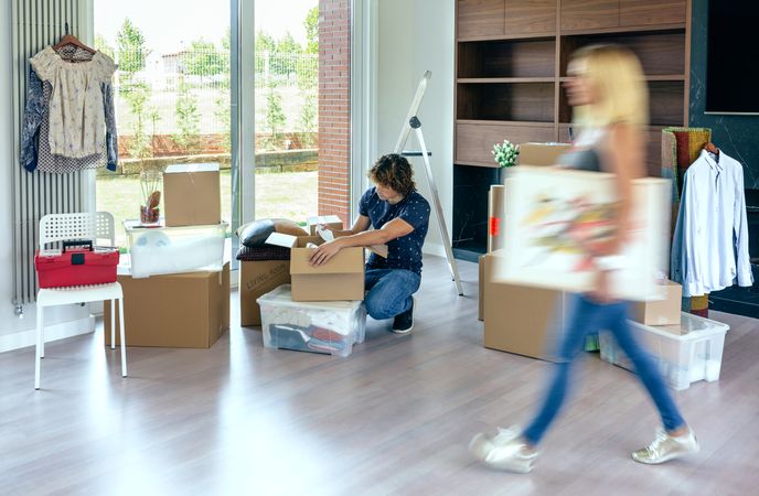Woman carrying painting while husband unpacks
