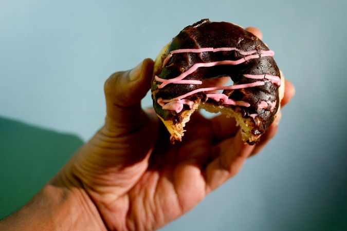 Hand holding a chocolate donut with bite