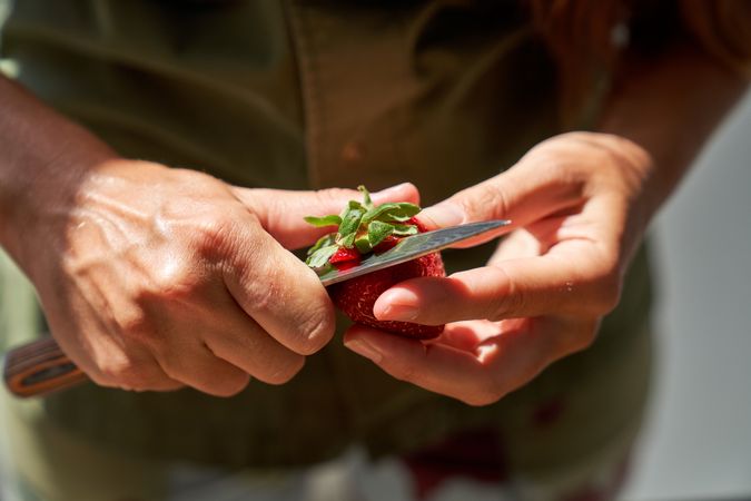 Unrecognizable person cutting strawberry with knife