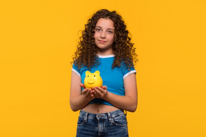 Girl holding piggy bank, focusing on traditional savings