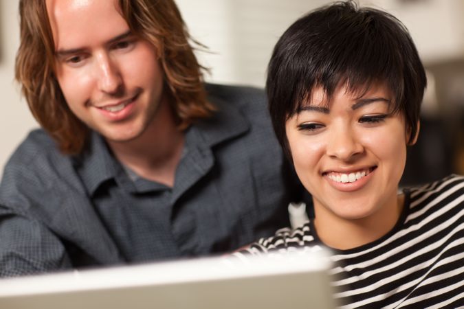 Happy Young Man and Woman Using Laptop Together