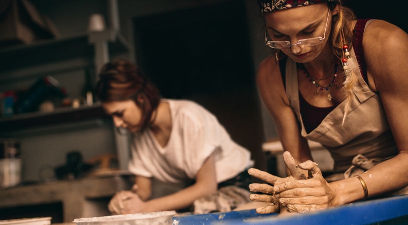 Two female artists at a pottery workshop making clay pots