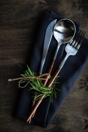 Cutlery set on wooden background with rosemary garnish