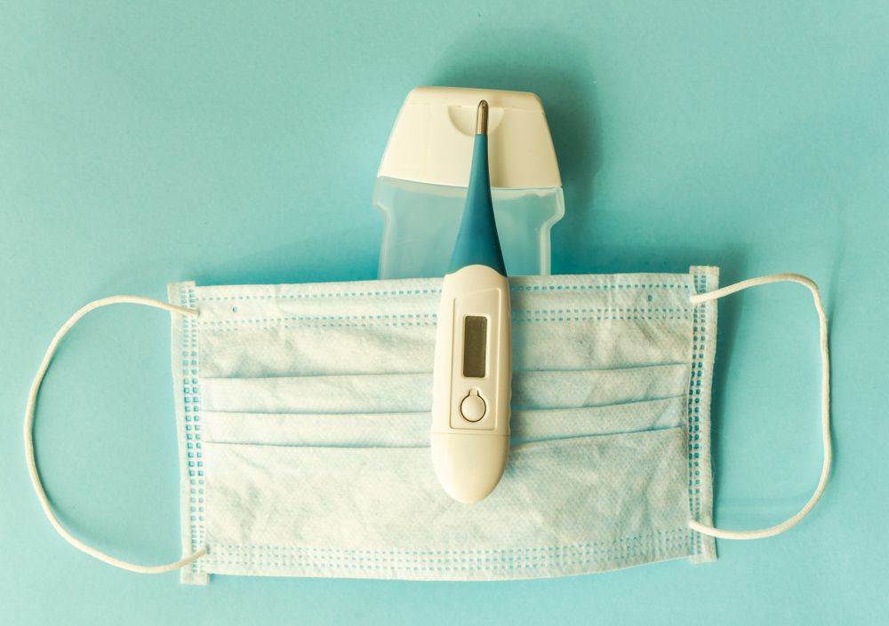 Covid-19 virus concept of facemask and digital thermometer