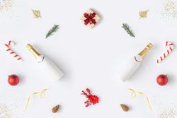 Holiday decorations; Champagne, candy cane and present, arranged symmetrically on light background