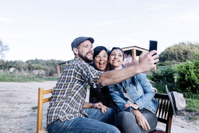 Three people sitting outdoors and taking a selfie
