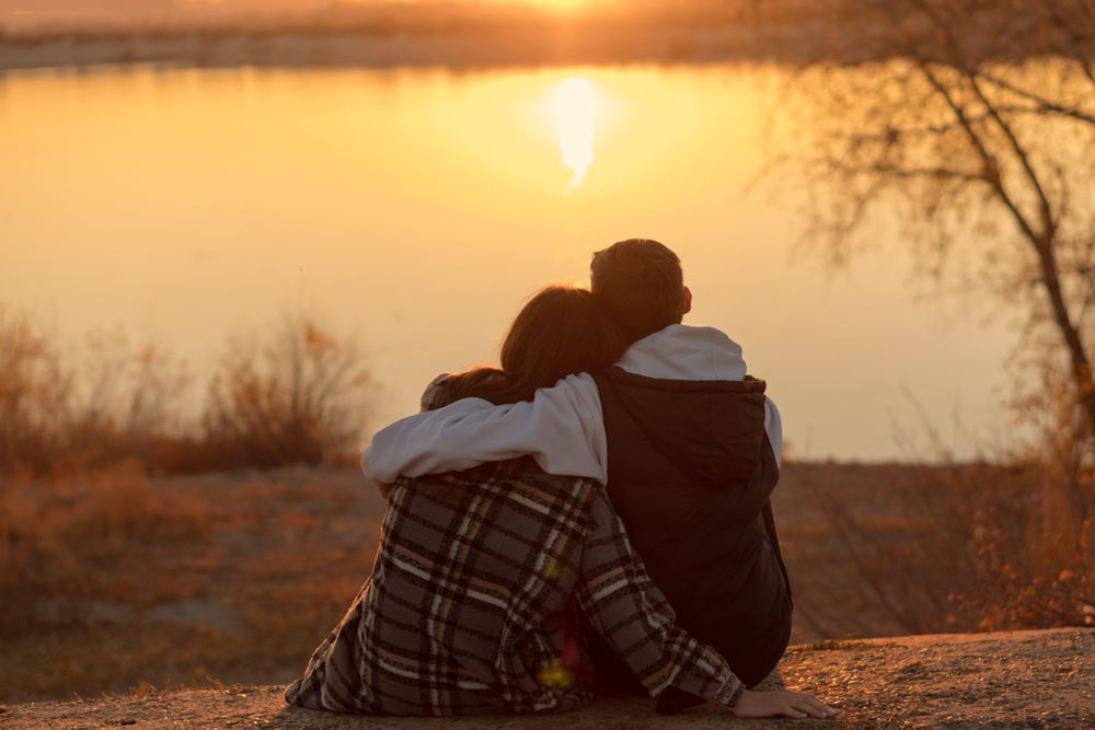 Couple sitting sunset lake