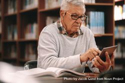 Older male working on tablet in college library 0vypxb
