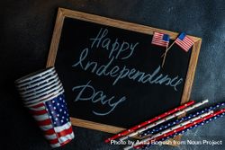 Chalkboard with the words "Happy 4th of July" with American flag straws and cups 4jV6LJ