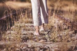 Long haired woman standing on railways overgrown with dry grass