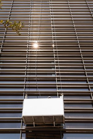 Faceless male window washer cleaning high building facade in construction