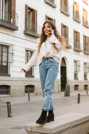 Smiling woman talking on smartphone and walking on border