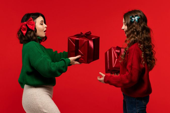 Woman receives shiny red present from girl in festive scene
