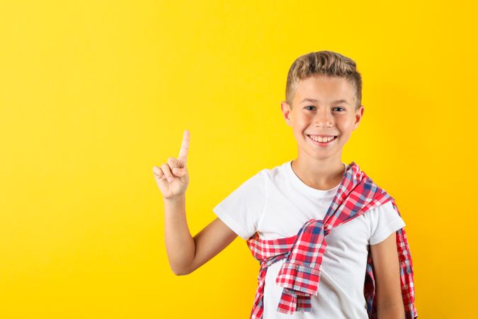 Happy boy against yellow background, space for text
