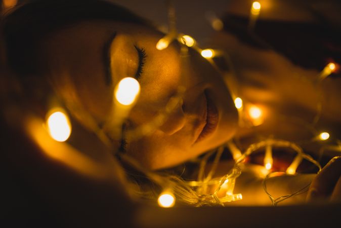 Woman lying surrounded by light garland