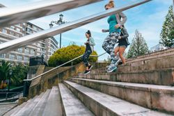 Fit females training running down stairs in town