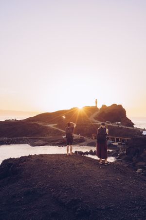 Travelers taking photo on seaside at sunset