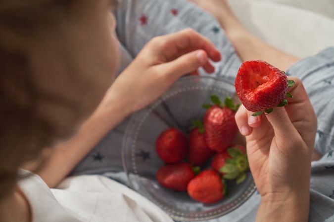 Unrecognizable boy eating strawberry from bowl