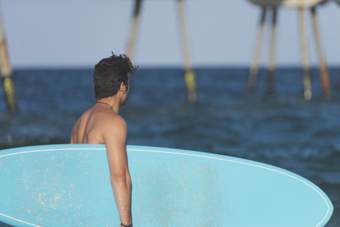 Male surfer with blue board enjoying the view of the water