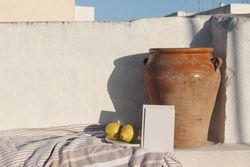 Blank greeting card, invitation mock up in sunlight leaning on vintage olive clay pot and fresh lemons fruit