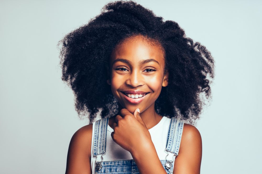 Portrait of happy girl smiling with hand on chin