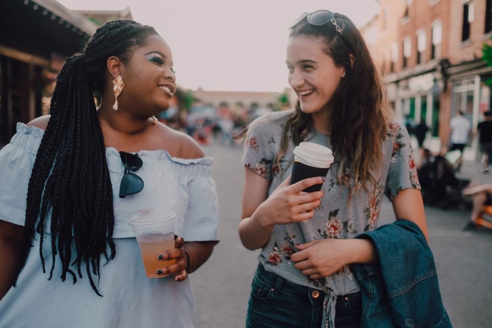 Happy multiethnic laughing modern women with coffee cups