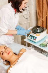 Female client lying in medspa as beautician prepares for treatment