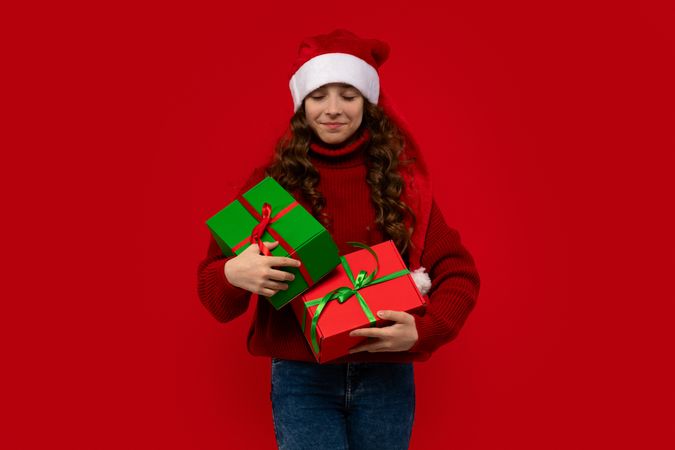 Girl in Santa hat looks down at Christmas presents